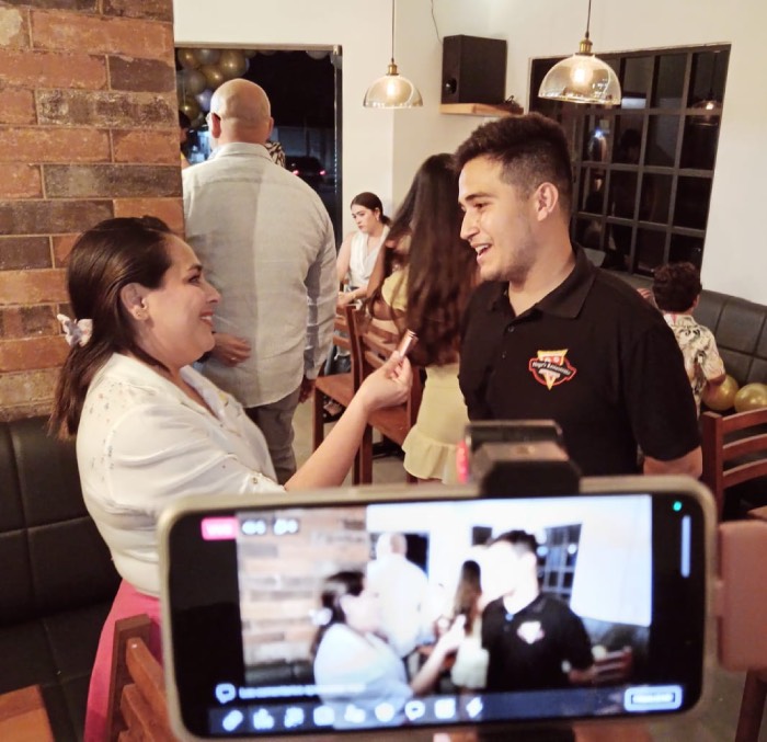 Celular grabando entrevista de fondo en negocio local Hugos Pizza