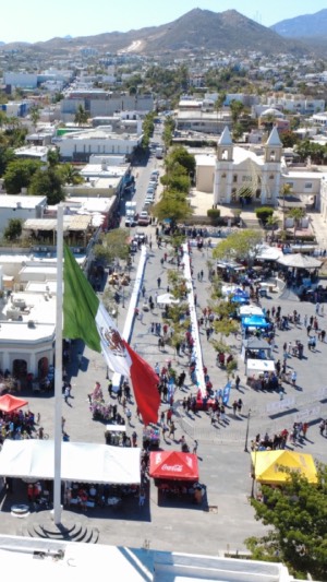 Bandera de México en el asta, en la plaza Antonio Mijares en San José del Cabo del fondo se ve la Mision de San José